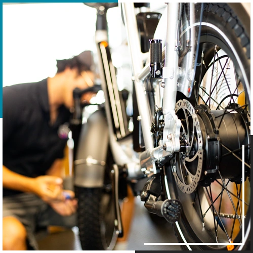 Back view of an ebike while a bike mechanic repairs the ebike.